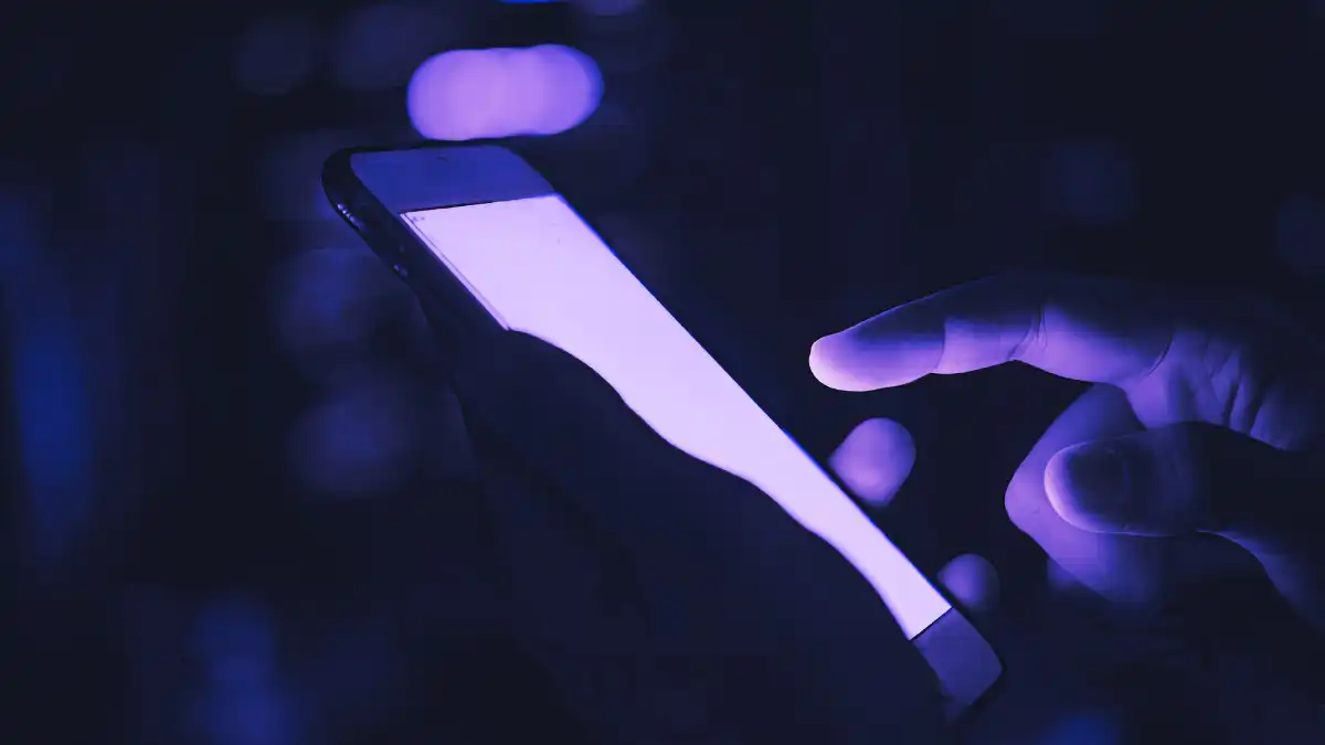 Teen using smartphone in dark environment showing continued social media use despite Australia’s under-16 ban