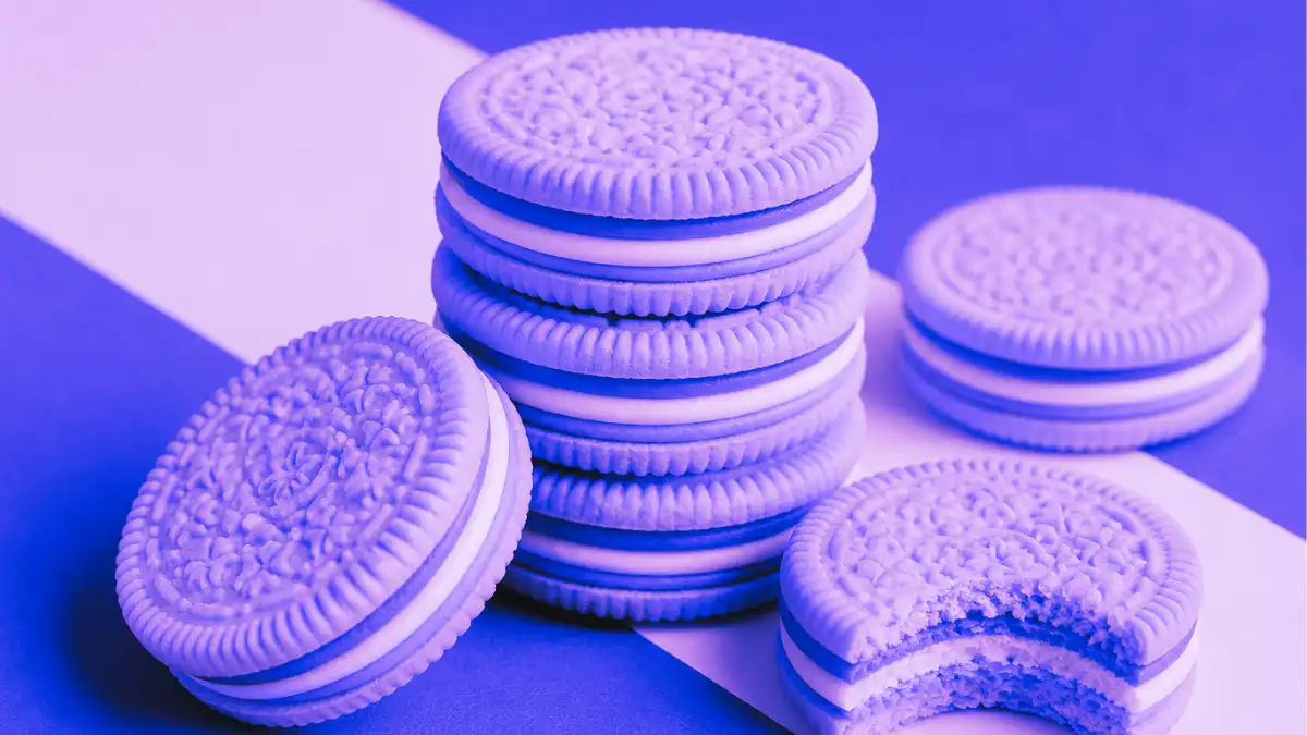 Stack of Oreo cookies with one bitten cookie, styled in blue and purple lighting to highlight product texture and layered creme filling.